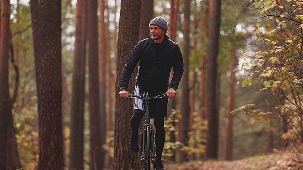 Un homme en tenue d'entraînement fait du vélo dans la forêt.